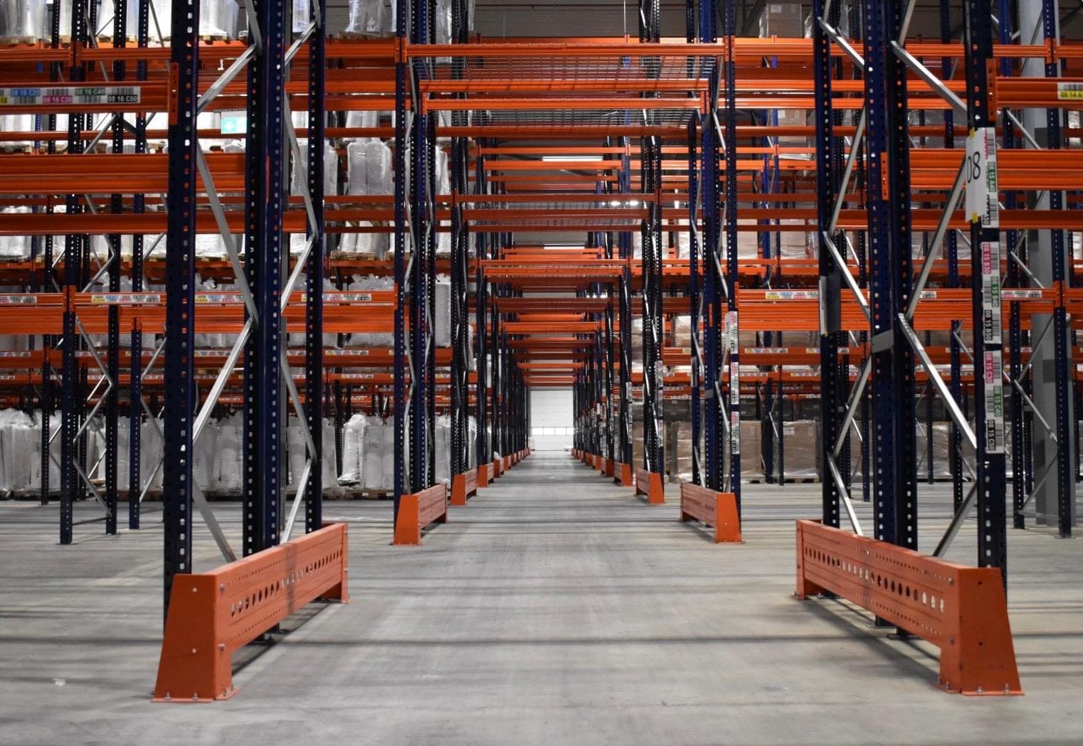 Magazijngang met blauw-oranje palletstellingen vol opgeslagen pallets